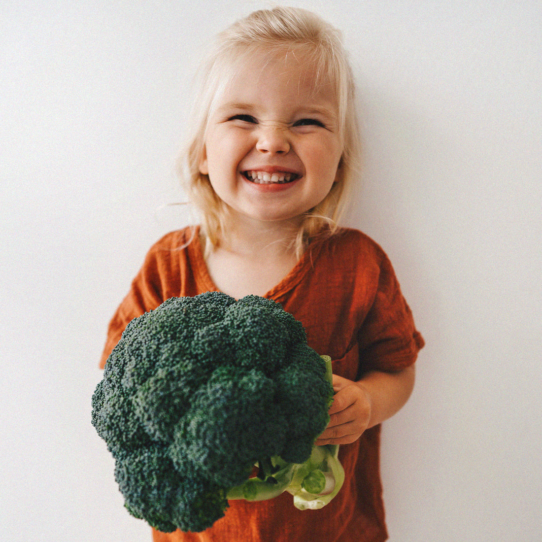 Petite fille souriante tient un brocoli